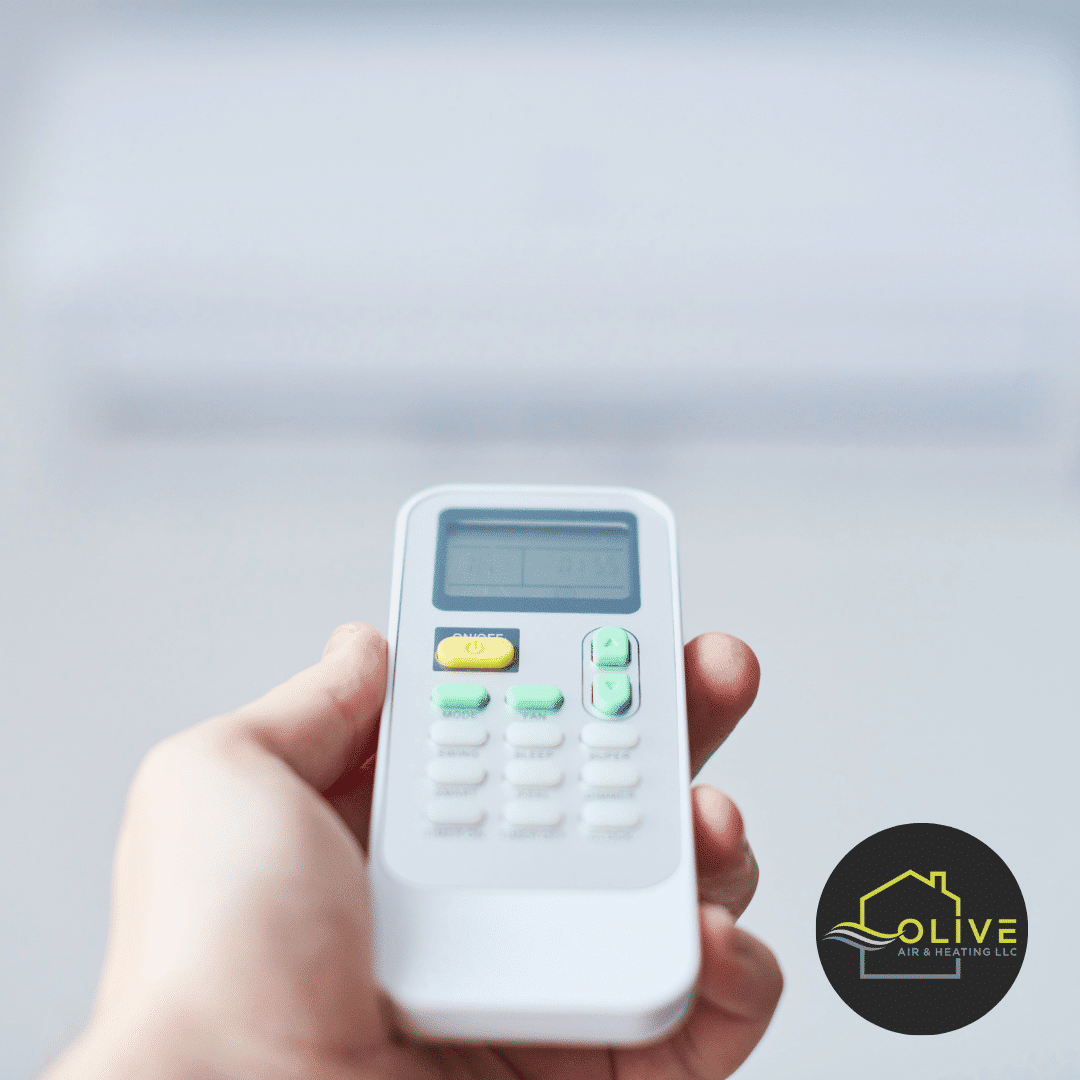 A hand pressing the remote control to adjust the AC settings for optimal comfort.