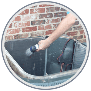 AC & Heating Tune-Up Special 3 HVAC technician carefully cleaning the outdoor coil of an air conditioning unit