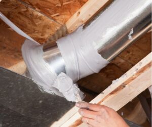 A technician applying sealant to an HVAC duct joint in an attic, ensuring airtight duct sealing in Phoenix for improved energy efficiency.